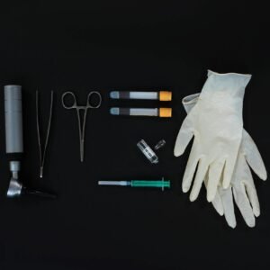 Flat lay of essential medical tools on a black background, including gloves and syringe.